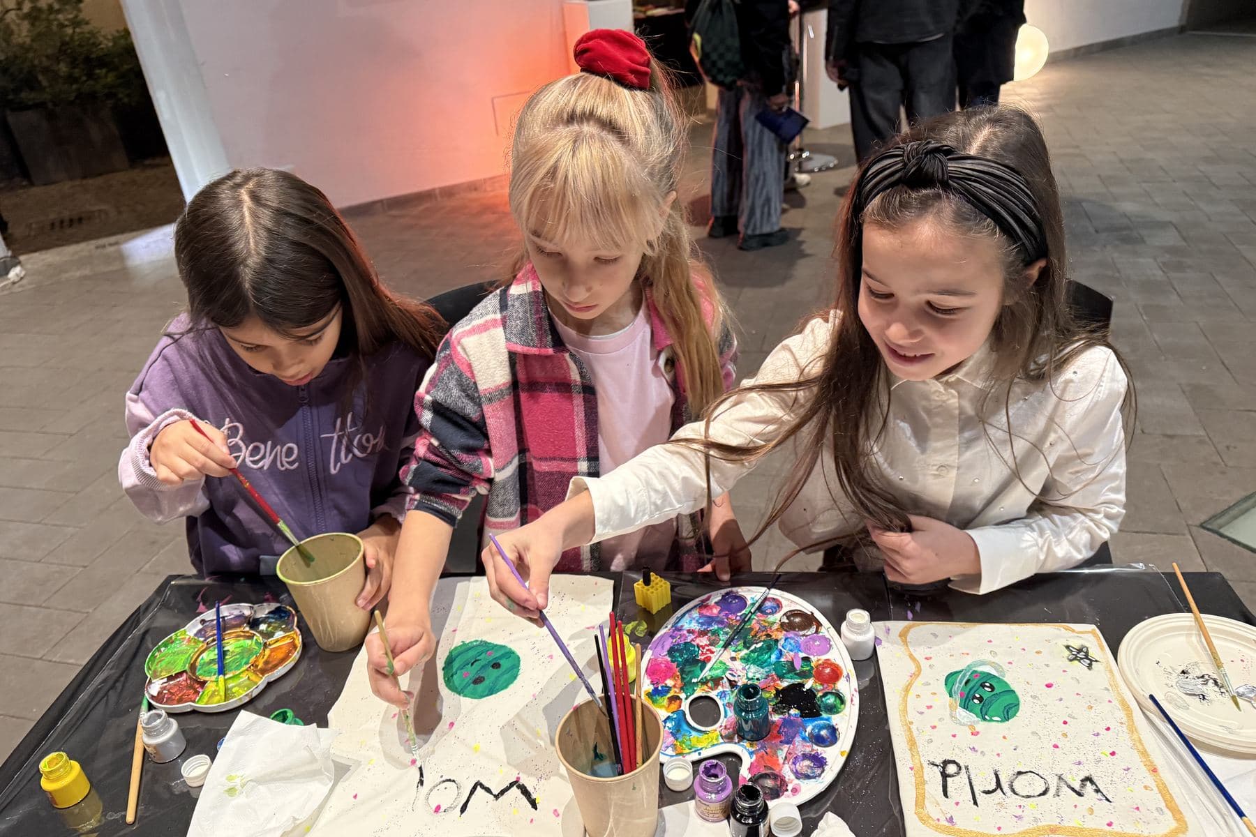 Tre bambine dipingono la propria t-shirt in cotone organico Farway Milano durante il laboratorio Little Couture Atelier a Milano